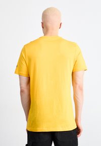 Nike Sportswear TEE - T-shirt imprimé - university gold